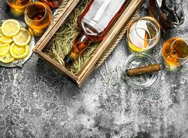 Cognac background. A bottle of cognac with lemon wedges and a cigar. photo