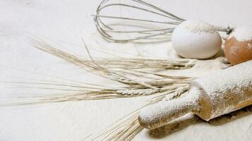 With the rolling pin whisk and ears of wheat in flour. photo