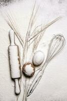 With the rolling pin whisk and ears of wheat in flour. photo