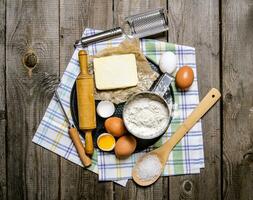 preparación de el masa. ingredientes para el masa - huevos, manteca, harina, sal y herramientas en el tela. foto