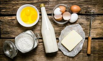 preparación de el masa. ingredientes para el masa - leche, huevos, manteca, harina y batidor. foto