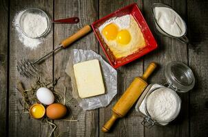 preparación de el masa. ingredientes para el masa - huevo, harina, manteca, agrio crema, y batidor con un laminación alfiler. foto