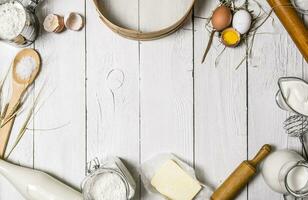 Baking background. Ingredients for the dough - Milk, eggs, flour, sour cream, butter, salt and different tools. photo