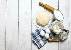 Preparation of the dough. Ingredients for the dough - flour, eggs, sour cream with a rolling pin and whisk. photo