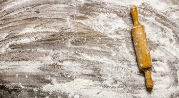 The rolling pin with flour on wooden table. photo