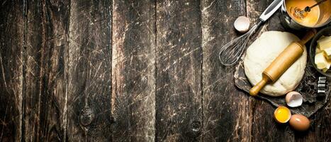 Dough background. The pastry with a rolling pin and ingredients. On a wooden table. photo