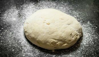 Dough background. Fresh dough with sifted flour on a rustic background. photo