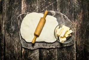 Dough background. dough with butter and rolling pin. On wooden background. photo