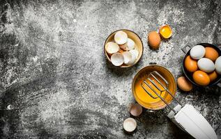 Dough background. Preparation of the dough. Whisking fresh eggs in the bucket mixer. On rustic background. photo