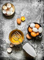 Dough background. Preparation of the dough. Whisking fresh eggs in the bucket mixer. On rustic background. photo