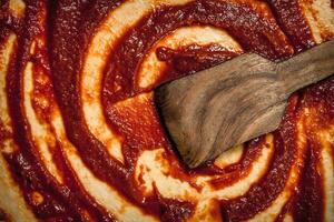 Preparation of pizza. Application of tomato sauce on the rolled dough. photo