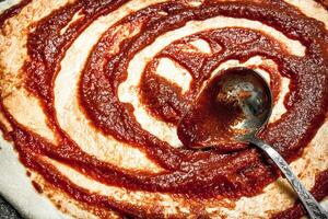 Preparation of pizza. Application of tomato sauce on the rolled dough. photo