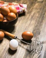 The eggs in the bowl with the whisk on the fabric. photo