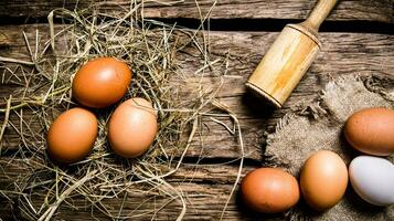 huevos en el heno con un mano de mortero . en de madera mesa. foto