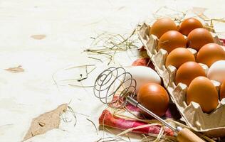 The cassette with eggs, hay and whisk on the fabric. photo