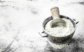 Flour with a scoop in a bowl. photo