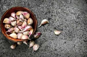 Peaces of fresh garlic in a wooden bowl. photo