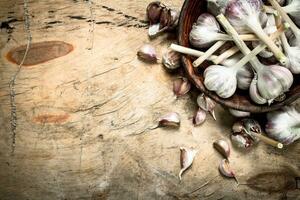 Fresh garlic in a bowl. On wooden background. photo