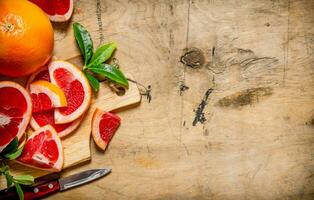 Sliced grapefruit on a wooden Board with leaves. photo