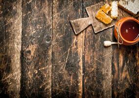 Honey pot and honeycomb with a wooden spoon. photo