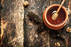 The honey in the pot with the nuts and cones. photo