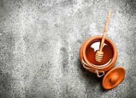 Fresh honey in a clay pot with a wooden spoon. photo