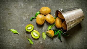 Fallen bucket with kiwi fruit and leaves. photo