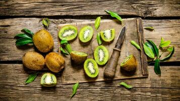 Sliced kiwi on the old board with leaves . photo