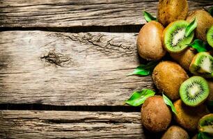 Fresh kiwi with leaves. On wooden background. photo