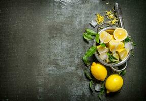 Fresh lemons in a saucepan with leaves and zest. photo