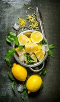 Fresh lemons in a saucepan with leaves and zest. photo
