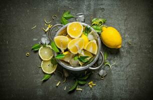 Fresh lemons in a saucepan with leaves and zest. photo