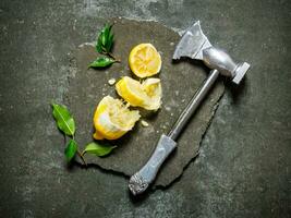 Axe with lemon and leaves on a stone stand. photo