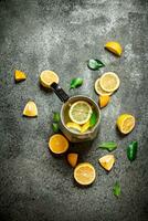 Cold lemonade in a jug with slices of lemon and green leaves. photo