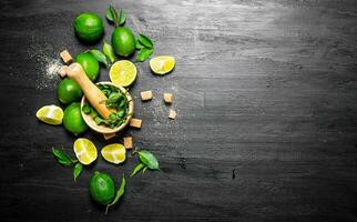 Lime background. The mortar with mint, sugar , lime slices and leaves . photo