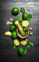 Lime background. The mortar with mint, sugar , lime slices and leaves . photo