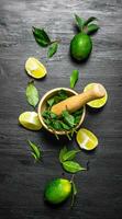 Lime background. The mortar with mint , lime slices and leaves . photo