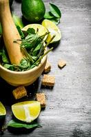 Lime background. The mortar with mint, sugar , lime slices and leaves . photo