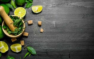 Lime background. The mortar with mint, sugar , lime slices and leaves . photo