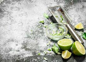 Fresh limes with grater and zest in a bowl. photo