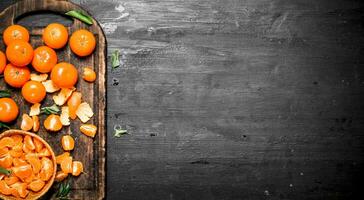 Peeled tangerines with green leaves. photo