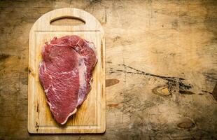 A large piece of raw fresh meat on cutting Board. photo