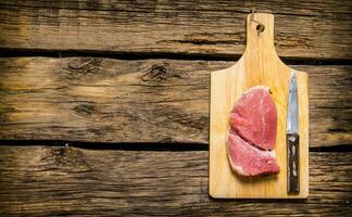 Steaks from raw meat with a butcher knife. photo