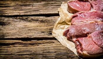 Raw fresh meat on paper. On wooden background. photo