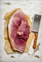 A piece of raw meat with a butcher knife on the paper. photo