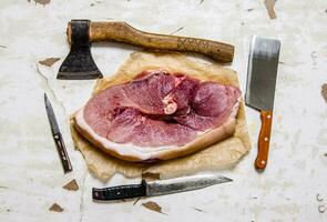 A piece of raw meat with a butcher knife on the paper. photo