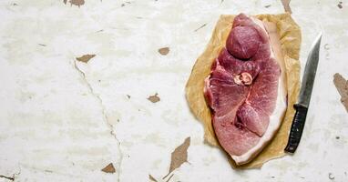 A piece of raw meat with a butcher knife on the paper. photo