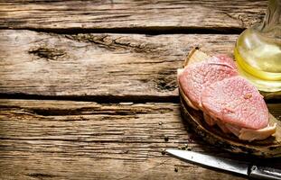 Fresh raw meat with knife and oil on a wooden stand. photo