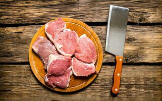 Pieces of raw meat with knife on cutting Board. photo