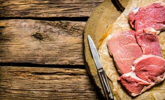 Raw steak with a knife on a wooden stand. photo